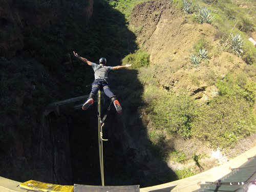 Junger Mann springt mit Bungee-Jumping von der Calzada-Brücke, erlebt den Nervenkitzel und genießt die Aussicht, während er im freien Fall hinabsteigt