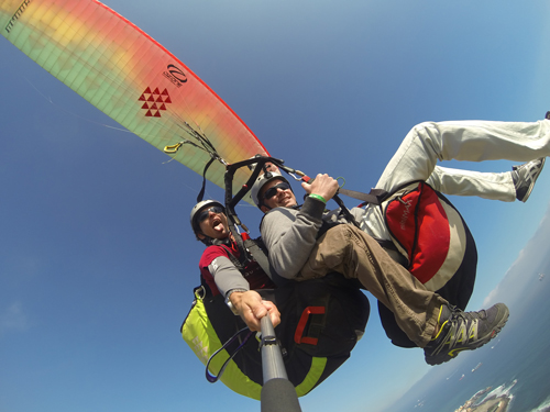Tandem-Gleitschirmflug über die atemberaubende Küste von Gran Canaria mit spektakulären Ausblicken auf den Ozean und die zerklüfteten Klippen unter einem klaren, blauen Himmel.
